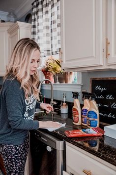 a woman is standing in the kitchen with her hand on the counter and looking at something