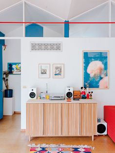 a living room filled with furniture and pictures on the wall next to a red couch