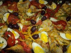 a pizza with eggs, tomatoes, olives and other toppings