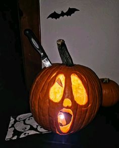 a carved pumpkin with an evil face on it and a knife sticking out of its mouth