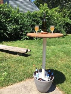 an outdoor table with two bottles and glasses on it