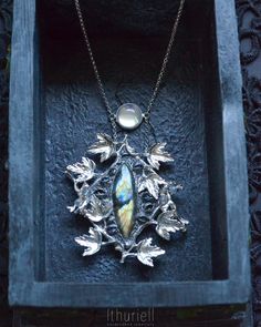 A beautiful statement necklace shaped into silvery leaves woven around a striking colorful labradorite in between many eyes. A wearable fairy tale of your own, one that follows you whenever you go: Wilderness has eyes, hidden in the lush greenery and twining branches. Would you meet its gaze when it's trained upon you?.. Labradorite, opalite, Zinc-based metal alloy, polymerclay and forest whispers. Dimensions: 2.5 x 2.25 inches / 6.3 x 5.7 cm Chain length is 18 inches / 46 cm + 2.5" for adjustin Mystical Labradorite Jewelry For Festivals, Silver Labradorite Necklace Nature-inspired, Silver Labradorite Necklace, Nature-inspired, Silver Labradorite Nature-inspired Jewelry, Silver Labradorite Necklace With Nature-inspired Style, Fantasy Moonstone Jewelry Gift, Nature-inspired Silver Labradorite Necklace, Handmade Mystical Necklaces, Nature-inspired Silver Labradorite Jewelry