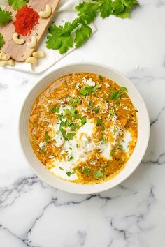 a white bowl filled with food sitting on top of a counter next to some parsley