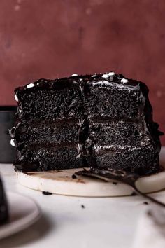 a slice of chocolate cake sitting on top of a white plate next to a fork