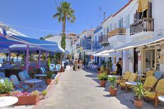 people are walking down an alley lined with tables and chairs