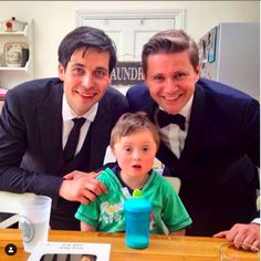 two men and a little boy sitting at a table