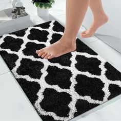 a black and white rug with a woman's feet on the floor in front of it