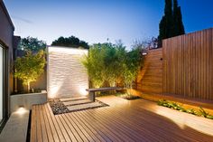 a wooden deck surrounded by plants and lights