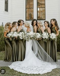 a group of women standing next to each other in front of a white building with flowers