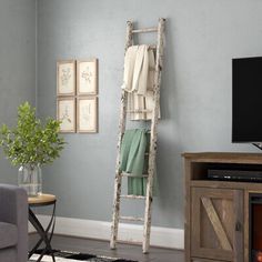 a living room with a ladder leaning up against the wall next to a tv and fireplace