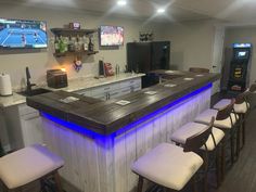 a bar with several stools in front of it and a television on the wall