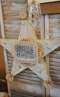 a christmas star hanging from the side of a window with ribbon around it and an ornament on top