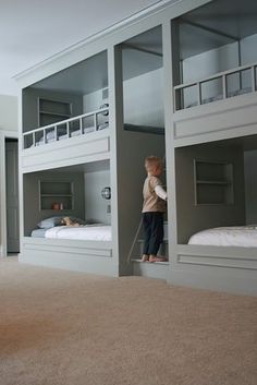 a young boy standing in between two bunk beds