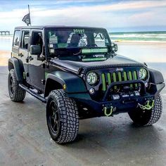 a black jeep parked on top of a sandy beach