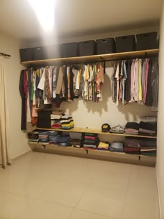 an organized closet with clothes hanging on the wall, and several bins full of shirts