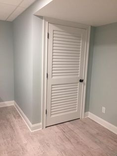 an empty room with a white door and wooden floor