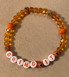 "Stretch Bracelet measures 7 3/8\" and reads BRING IT in white plastic with orange letters. You will feel empowered when you wear this bright orange stretchy bracelet! No matter the situation, you're ready, so BRING IT!  Twenty 6mm rondelle crystal beads in clear orange, five deeper orange 6mm Millefiori glass flower beads, and two 8mm opaque orange rondelle crystal glass beads make up this unique stretchy beaded EMPOWERMENT bracelet. Watch for more one of a kind ideas from my imagination, or op Casual Orange Stretch Bracelet With Letter Beads, Cute Adjustable Orange Beaded Bracelet, Orange Stretch Bracelet With Letter Beads, Cute Orange Bracelet, Adjustable Fun Orange Bracelets, Handmade Orange Novelty Bracelets, Hand-strung Orange Spiritual Bracelets, Orange Bracelet, Resin Bracelet