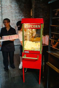 two people standing in front of a popcorn machine