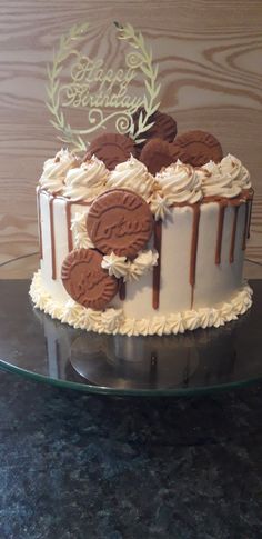 a birthday cake with cookies and frosting on top sitting on a glass platter