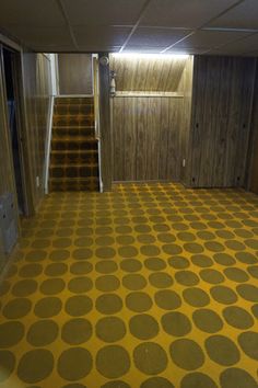 an empty room with yellow and brown carpeting on the floor next to a set of stairs