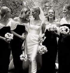 a group of women standing next to each other wearing dresses and holding bouquets in their hands