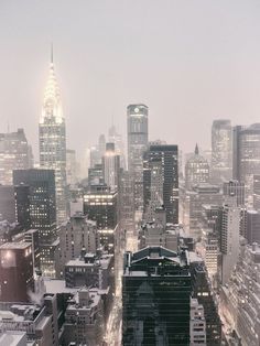 the city skyline is lit up at night with skyscrapers in the foreground and snow on the ground