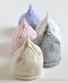 three knitted beanies sitting next to each other on top of a white surface