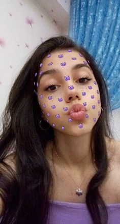 a woman with purple polka dots on her face is making a funny face for the camera