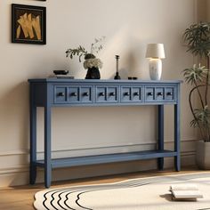 a living room with a blue console table next to a potted plant and pictures on the wall