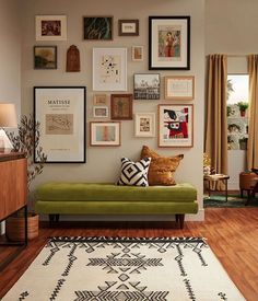 a living room filled with lots of framed pictures on the wall above a green couch