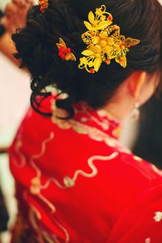 a woman in a red dress with yellow flowers on her hair is wearing a gold brooch