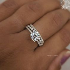 a woman's hand with a diamond ring on top of her finger and the bottom half of her wedding band