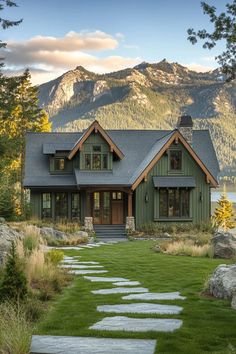 a green house with stone steps leading to the front door and side windows, along with mountains in the background