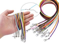 a hand holding a bunch of multi colored bracelets with chains attached to each strand