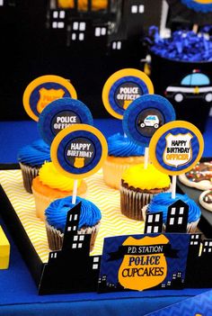 a table topped with cupcakes covered in blue frosting and yellow icing