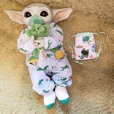 a baby yoda doll is holding a stuffed animal in its arms and wearing pajamas