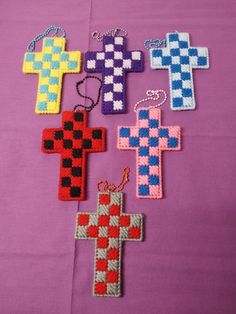 four cross shaped key chains sitting on top of a purple cloth covered table next to each other