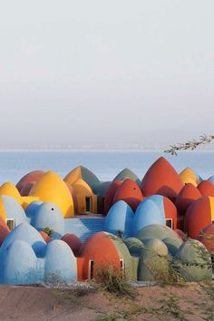 a group of colorfully painted houses sitting on top of a hill next to the ocean