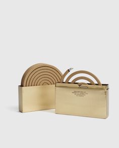 a set of four gold colored coasters in a metal box with wooden handles and straps