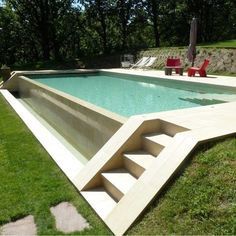 an empty swimming pool in the middle of a grassy area with stairs leading up to it