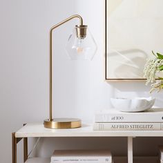 a table with some books and a lamp on it next to a vase filled with flowers