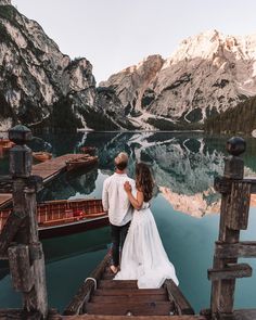 a bride and groom are standing on a dock