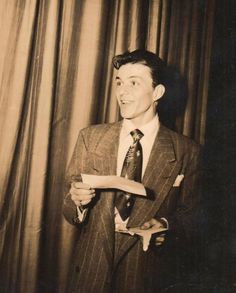 a black and white photo of a man in a suit holding a piece of paper