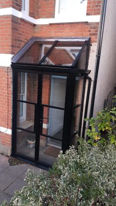 a small black glass house sitting next to a brick building