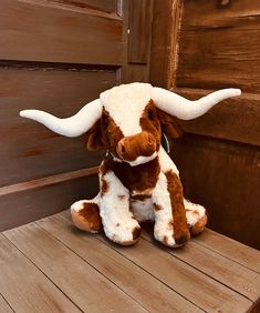 a stuffed cow sitting on top of a wooden bench