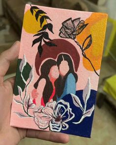 a person holding up a small painting with flowers on it