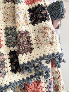 a crocheted blanket is being held up by someone