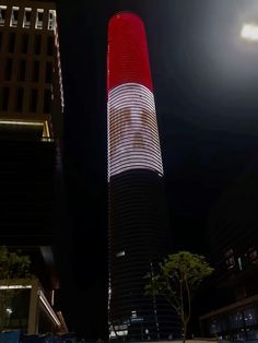 a tall red and white building in the city at night