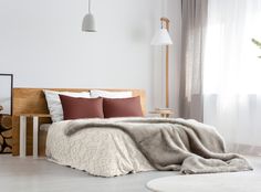 a bedroom with white walls and flooring has a large bed covered in a blanket