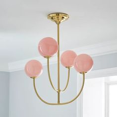 a pink and gold chandelier hanging from a ceiling in a room with white walls